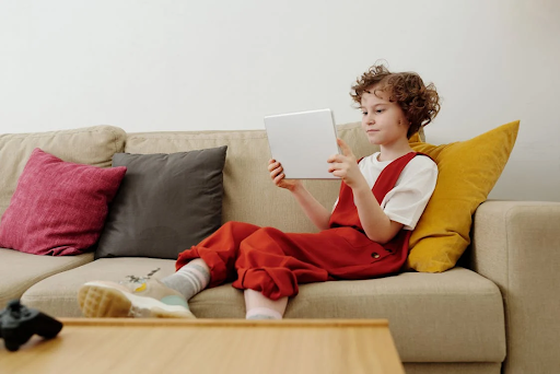 girl seating on a couch looking into tab