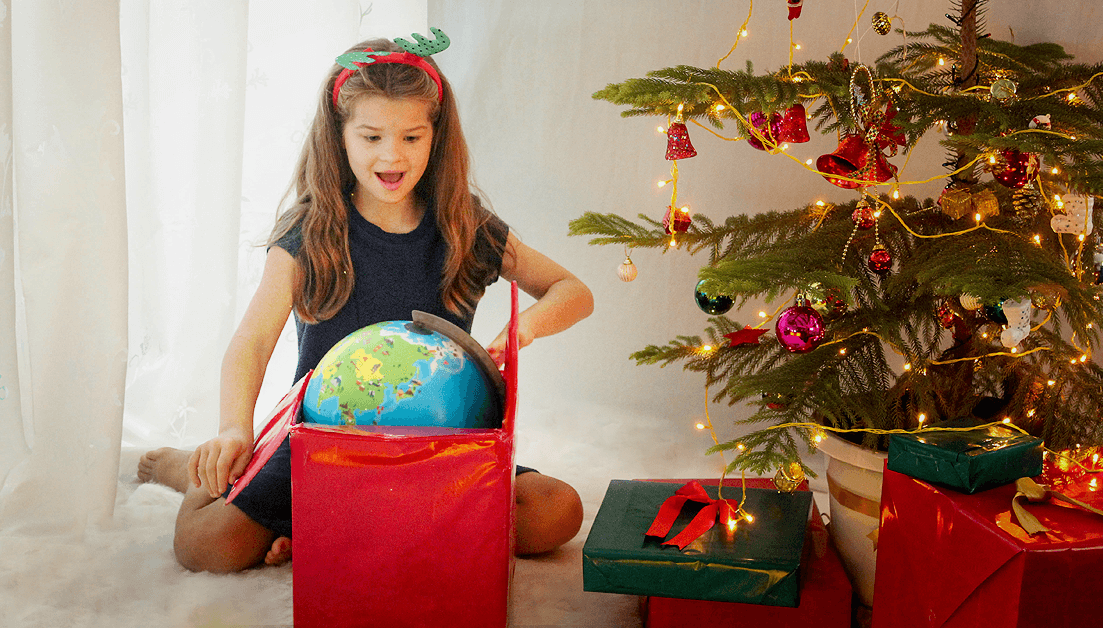 girl opening gift near christmas tree