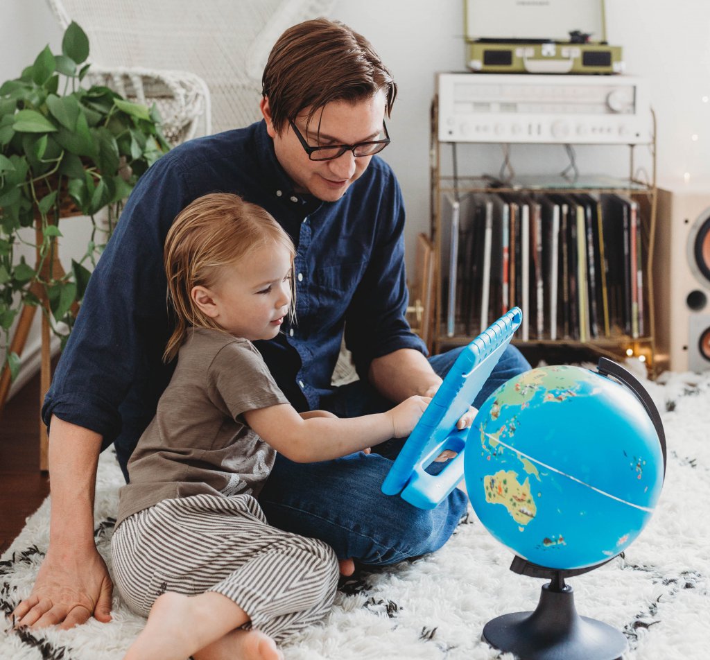 parent and kid homeschooling with globe