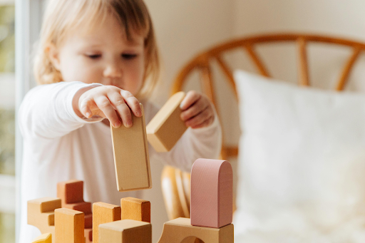 small girl playing with wooden blocks