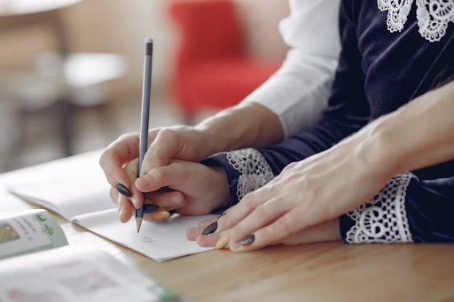 woman helping kid write